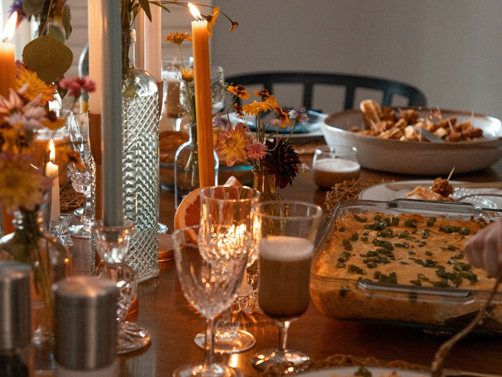 Mesa comprida posta com velas, flores e travessas de comida